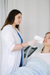 Female specialist performing laser therapy on patient at clinic